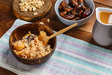 a plate of couscous with dried fruits and nuts on a wooden table on a napkin with a wooden spoon.