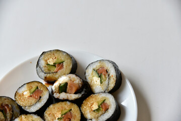 Rice rolls with salmon and cheese on a white plate. Japanese sushi.