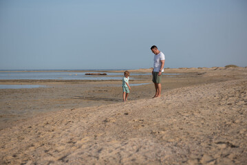 Rear view of father and son walking on the beach