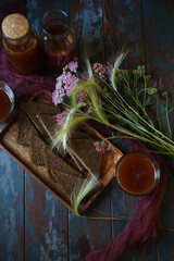 Traditional homemade beverage kvass in glasses and bottles with summer bouqute of rye and yarrow,...