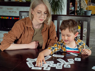 Mom teaches her son how to say the words on the cards at home at the table