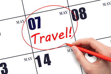 Hand drawing a red circle and writing the text TRAVEL on the calendar date 7 May. Travel planning.