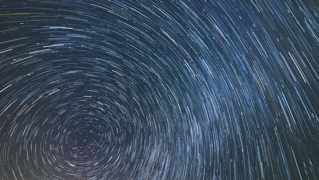 Star trail of stars moving in the spring night sky around the North Star. Landscape with movement of stars, time lapse
