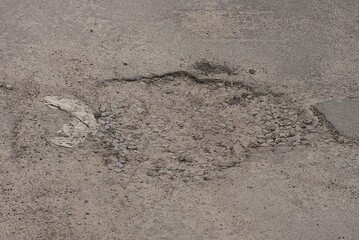 one big pothole on the gray asphalt road on the street