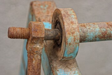 old long rusty brown iron construction from a nut and a bolt on blue plates of a beam in the street