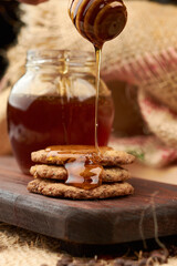 Homemade cookies made in an artisanal way, using a wooden server, honey is placed on a cutting board, in the background a jute bag made of natural fiber