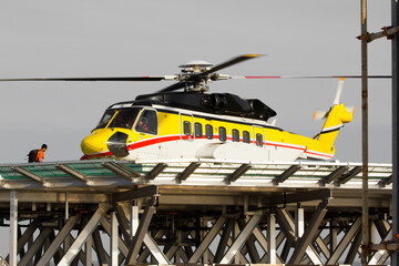 A helicopter on top of a offshore oil-platform transporting roughnecks to nearby rigs