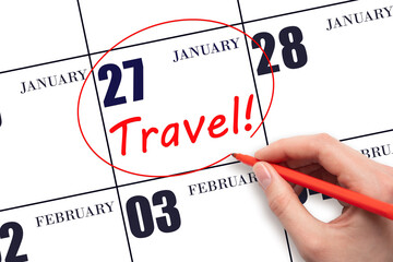 Hand drawing a red circle and writing the text TRAVEL on the calendar date 27 January. Travel planning.