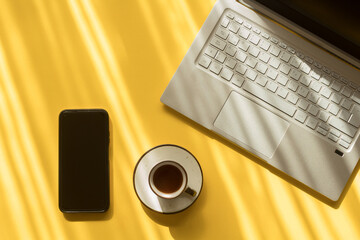 Laptop, celular, café en mesa con el rayo del sol