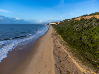 Amazing land cliffs with the golden hour of the rising sun and beautiful beach in Parrancho, Arraial da Ajuda, Bahia, Brazil, South America. Aerial drone view.