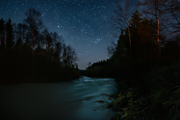 A magical starry night on the mountain river bank.