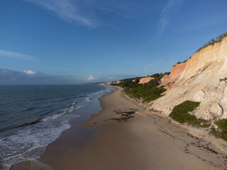 Amazing land cliffs with the golden hour of the rising sun and beautiful beach in Parrancho, Arraial da Ajuda, Bahia, Brazil, South America. Aerial drone view.