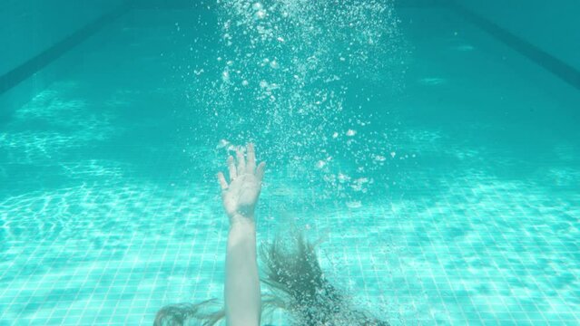 Blue swimming pool, underwater shooting, sunny day. Chubby girl drowns in water. Slow motion