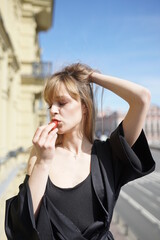 In the afternoon, in the light of the sun, on her balcony, touching a girl in black pajamas enjoys strawberries