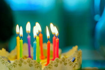 Nine colorful burning candles on a festive cake