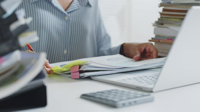 Close up of asian woman working hard with stack of document and laptop computer at office