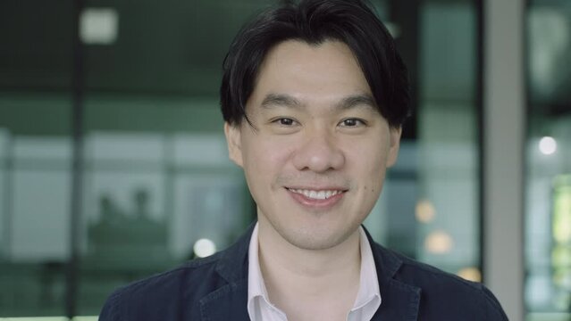 Portrait of handsome Asian businessman standing smiling and looking at camera in the airport lounge. Headshot of happy young male business in the office. Closeup face of cool man trendy and friendly. 