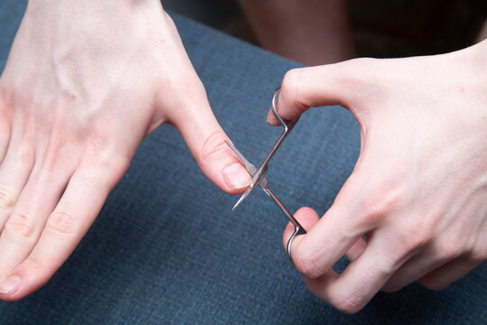 A young man cuts his fingernails with nail scissors.