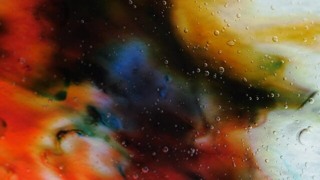 Transparent space liquid is filled with drops of red, blue, yellow and green paint.