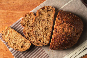 Sliced loaf of bread on cutting board, loaf of artisan grain bread, top view