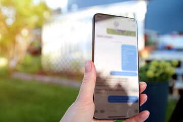 Woman  is checking text messages  holding smartphone outside.