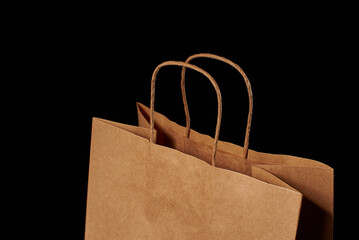 Close-up of the twisted pens of a brown paper bag insulated on a black background.