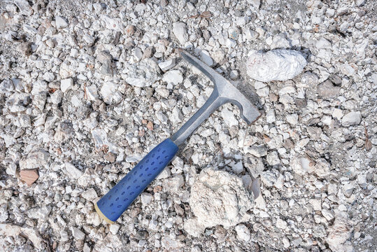 Chisel edge rock pick, geologist exploration tool over natural magnesite rocks background in abandoned magnesium mine in Cyprus