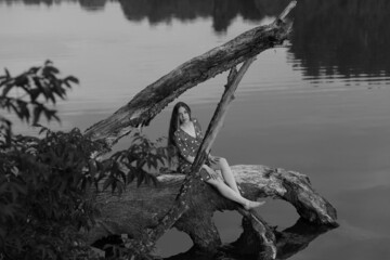 Beautiful woman on an old tree in the middle of the lake in black and white