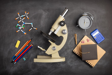 Back To School and education Concept. Alarm clock, microscope and over supplies on blackboard background. Copy Space, top view flat lay