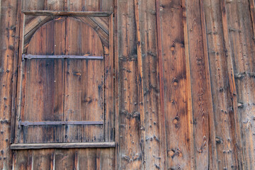 Old wooden window with vintage hinges on a wooden wall