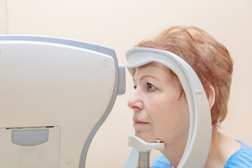 An adult woman at an ophthalmologist's appointment checks her vision on a special apparatus....