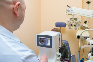 A male ophthalmologist checks the eyesight of a young girl using a modern vision tester