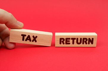 On a red background, wooden blocks, one of them in hand. The blocks are written - TAX RETURN