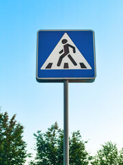 the crosswalk, informational road sign on pole against landscaped background