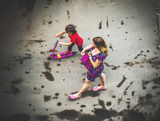 mother and daughter walk along dirty asphalt, above view
