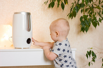 Little baby boy touch the button on air humidifier.