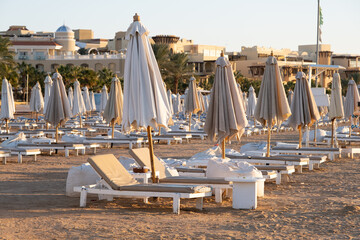 Empty sun loungers by the sea and closed umbrellas. Morning on the seashore. Beach chairs.