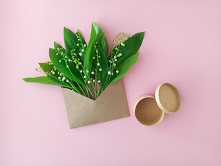 A bouquet of white forest lilies of the valley in a brown, corrugated envelope. A small round box for decoration. The awakening of spring. Delicate fragrance of perfume