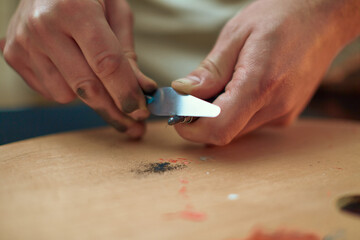  Artist sharpens pencil graphite by palette knife preparing for drawing. Closeup male painter...