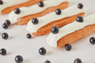 eclairs with currant berries on a light background background