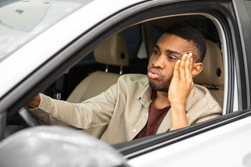 Stressed man sitting in the driver's seat of a car looks into the windshield 