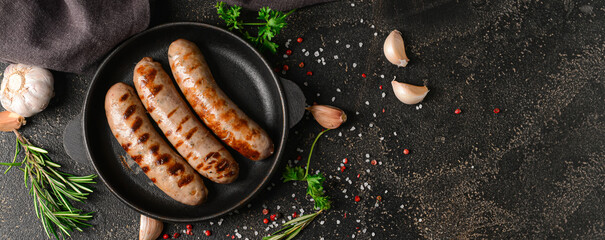 Frying pan with delicious grilled sausages and spices on dark background with space for text - obrazy, fototapety, plakaty