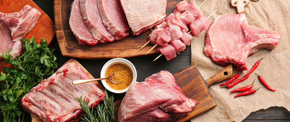 Composition with raw pork meat, spices and herbs on dark wooden background