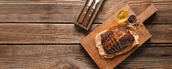 Board with tasty roasted meat on wooden background with space for text