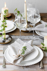 Rustic zero waste wedding decor with natural elements. Wooden table, candles, linen napkins, branches with green leaves. Eco-friendly decoration for the special dinner. Romantic and cozy place