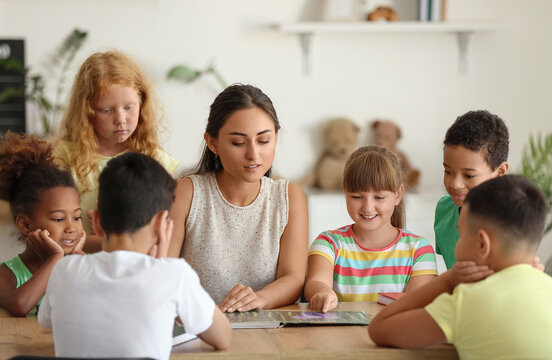Little children having literature lesson with their teacher in classroom