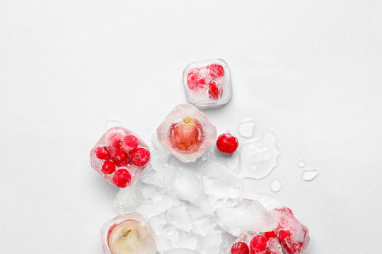 Fresh berries frozen in ice on light background