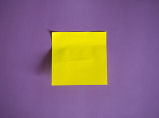 blank yellow paper sticker for notes and pen on purple background