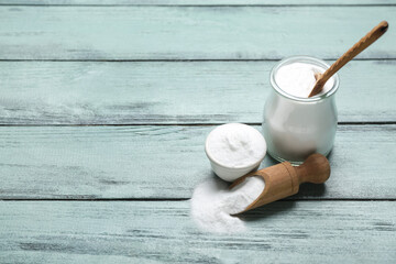 Jar, bowl and scoop with baking soda on color wooden background