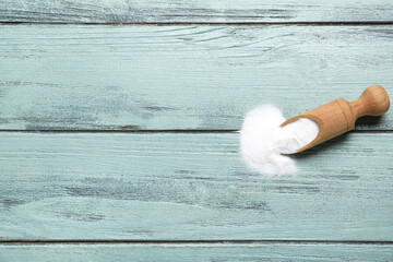 Scoop with baking soda on color wooden background